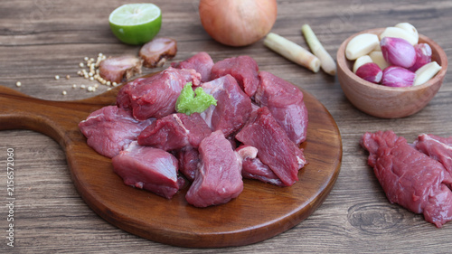 Canvas Print Raw organic slices beef on a wooden cutting board with kitchen table setting
