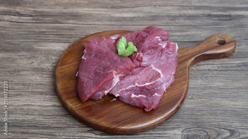 Photography Raw organic slices beef on a wooden cutting board with kitchen table setting