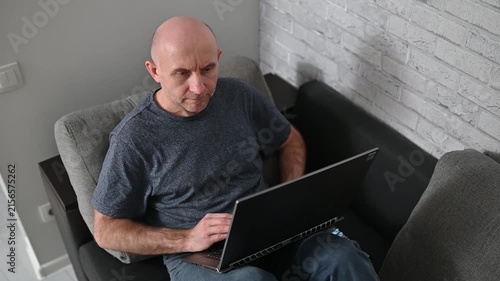 Relaxed mature man using laptop on sofa in modern apartment Full interior video HD