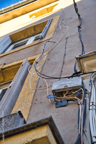 Messy cable installation on an old house facade.