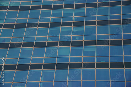 Blue glass curtain wall with a geometric grid and subtle interior reflections, creating a clean architectural background for corporate, design, and presentation use.