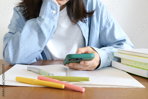 勉強に集中できずスマホを見る女性