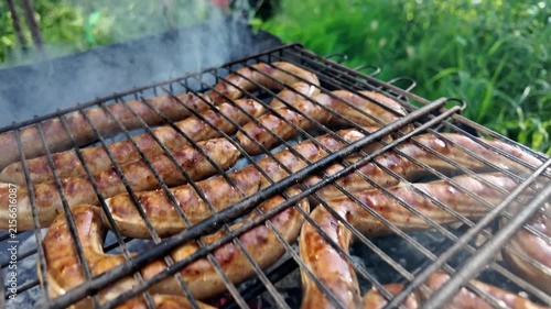 Meat sausages are fried in the grill grate. Cooking barbecue food on the grill with smoke.