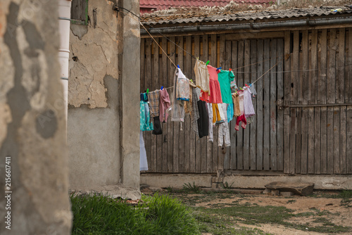 Colorful clothes drying on clothesline in old rustic courtyard with wooden shed in Talsi, Latvia