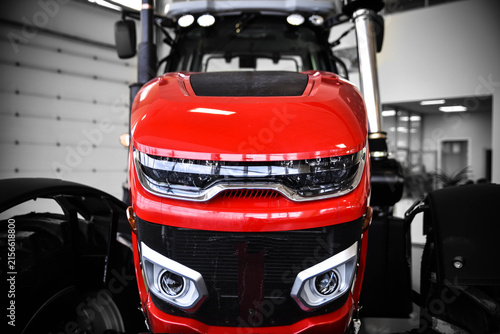 Close-up of a modern stylish red tractor. Detailed view of contemporary agricultural machinery highlighting its design, powerful construction, and advanced engineering.