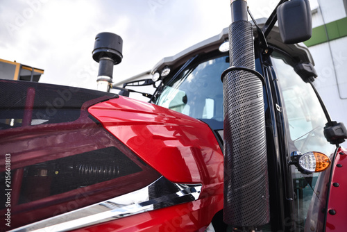 Close-up of a modern stylish red tractor. Detailed view of contemporary agricultural machinery highlighting its design, powerful construction, and advanced engineering.
