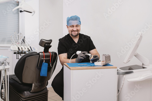 Doctor sits, dental technician uses 3D optical scanner to digitize physical dental model, transferring precise three-dimensional data to computer for digital dental design and CAD CAM manufacturing