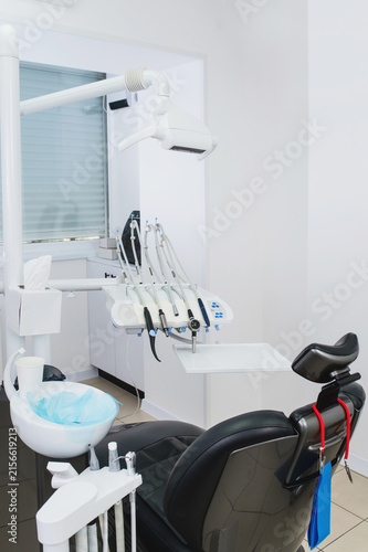 Dental equipment and chair in stomatology for treatment unit with professional dental handpieces, air water syringe, control panel, tubing and precision instruments arranged on modern dental chair ver