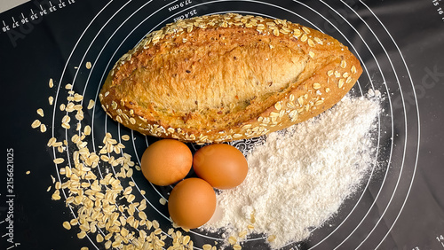 Obraz na plátne Homemade bread with oatmeal, eggs, and wheat flour on a kitchen mat