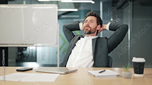 Professional finds peace after completing tasks. Relaxes at office desk. Experience success and satisfaction from achievements. Moment of calm amidst demanding business environment.