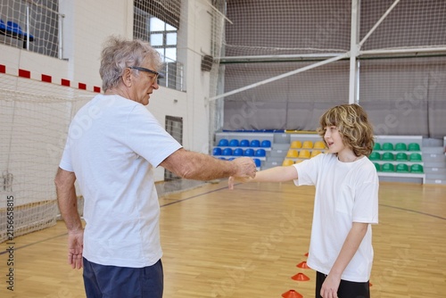 Fotografie Senior man and teenage boy shaking hands during recreational exercise on an indo
