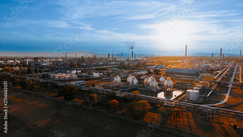 Bild auf Leinwand Solar glare over petrochemical refinery facility with round gas holders