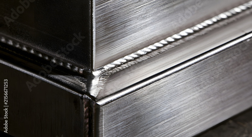 A clear view of a welded seam at the edge of two steel plates. Industrial imagery of fusion, construction, and manufacturing