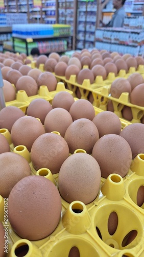 Fresh Brown Chicken Eggs in Yellow Cartons Displayed at Supermarket for Grocery Shopping and Food Production