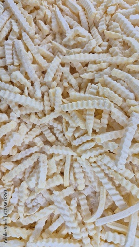 Close-up Full Frame Background of Frozen Crinkle Cut French Fries for Food Industry or Restaurant Menu Design