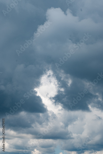Photography Vertical view of stormy clouds with a bright gap of sunlight piercing through