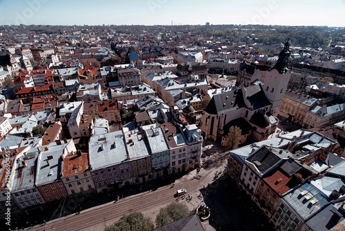 Bild auf Leinwand Aerial photograph of a historic Lviv old town featuring a prominent church, narrow cobblestone streets, tram tracks and rows of colorful rooftops under a clear sky, evoking heritage and urban charm