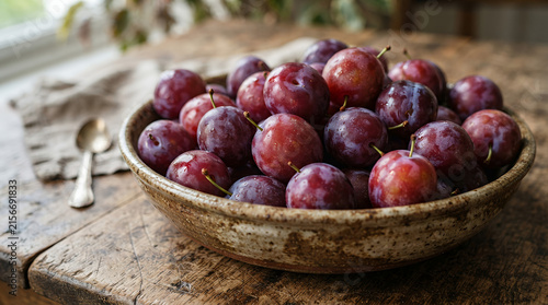 plums in a rustic bowl on a wooden table with natural light