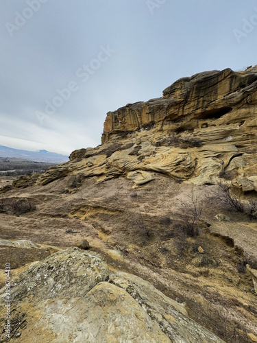 Sandstone cliff with winding formations and eroded rocky slope below.