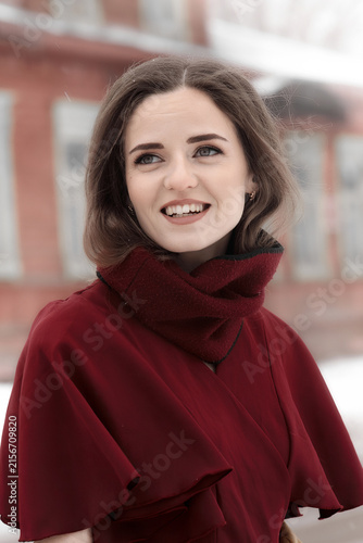 Portrait of a smiling young woman in a burgundy coat outdoors during winter. Natural beauty, lifestyle, fashion and seasonal concept.