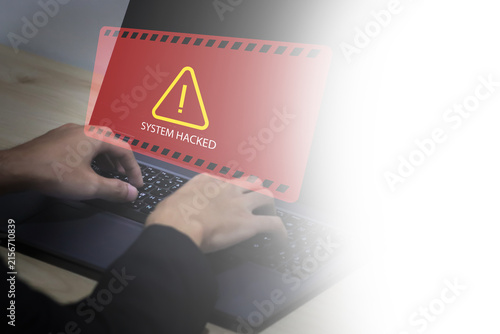 Business professional using laptop with hacked system alert, highlighting cybersecurity breach, ransomware attack, malware infection, data protection, cyber threat, network security, and digital risk.