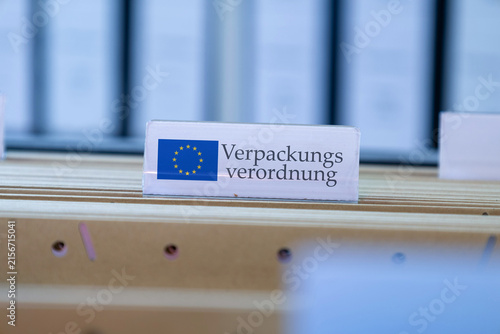 (Fotomontage) Schild mit der Aufschrift VERPACKUNGSVERORDNUNG an einem Hängemappenregister
