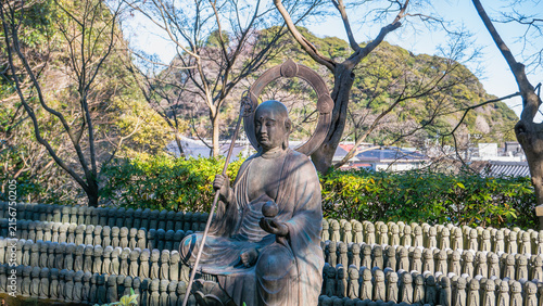 Bild auf Leinwand A bronze statue of Jizo surrounded by hundreds of small stone Jizo statues at Hasedera temple in Kamakura, Kanagawa prefecture, Japan