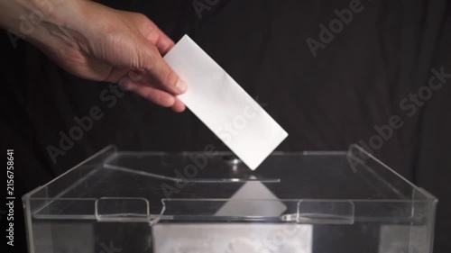 Voter holding ballot sheet above transparent box slot during global or US elections
