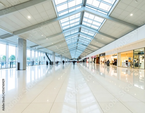Modern airport terminal with glass ceiling and travelers.