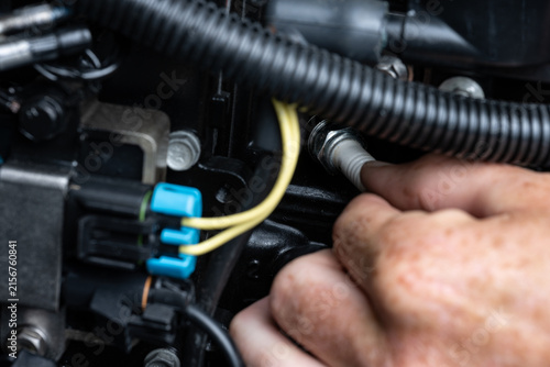 Hand Removing Spark Plug from Outboard Engine