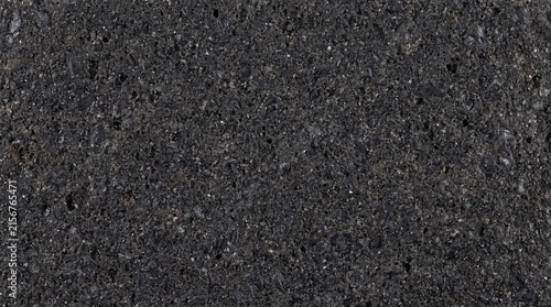 Dark grey basalt stone surface exhibits a rough porous texture suitable for architectural background applications.