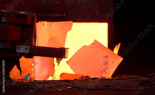 Konstfotografi A heated metal block emits a vivid orange glow inside an industrial furnace, held firmly by mechanical clamps