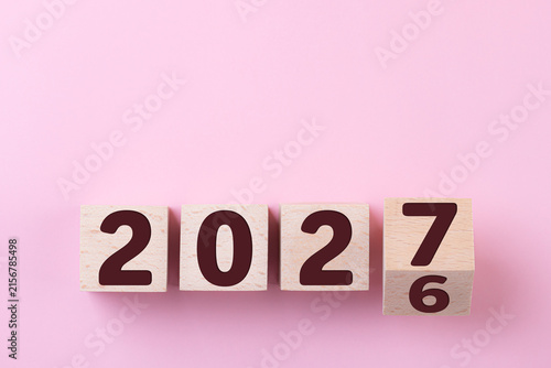 2027 Happy New Year. Wooden cube block change from 2026 to 2027 on pink. Concept 2027 New Year background. Business, resolutions, goals, inspiration, success, ideas