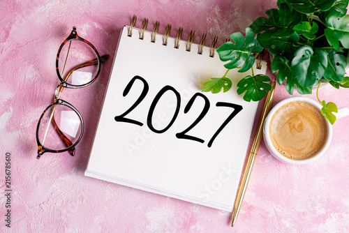 New year resolutions 2027 on desk. 2027 resolutions list with notebook, coffee cup on pink table. Goals, resolutions, plan, action, checklist concept. New Year 2027 template, copy space