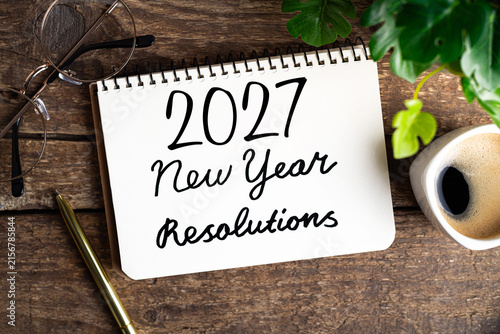 New year resolutions 2027 on desk. 2027 goals list with notebook, coffee cup, plant on wooden table. Resolutions, plan, goals, action, checklist, idea concept. New Year 2027 resolutions. Copy space