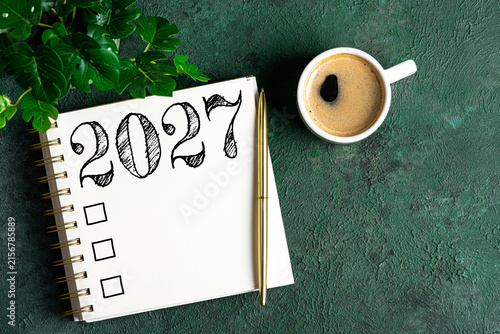 New year resolutions 2027 on desk. 2027 resolutions list with notebook, coffee cup on table. Goals, resolutions, plan, action, checklist concept. New Year 2027 template, copy space