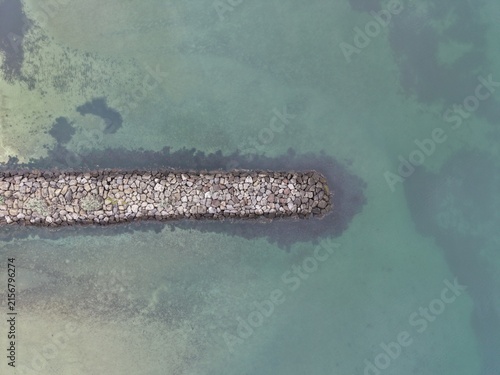 Картината върху платно Stone breakwater separating clear sea and shallow water