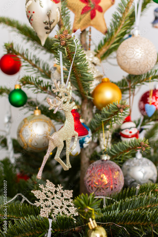 Fototapeta premium A Christmas tree stands with many colorful ornaments hanging from its branches. Each ornament shows different shapes and colors, celebrating the festive season and bringing joy to the home