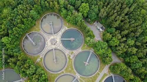 Aerial view of circular wastewater treatment tanks in forest