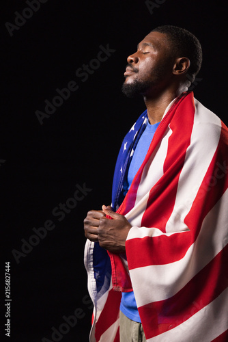 Konstfotografi Mid-adult African American man in blue shirt standing wearing US flag in studio,