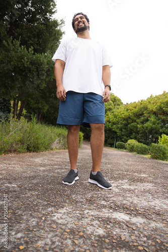 Mid-adult African American man standing on paved park path wearing casual athletic clothing, watch