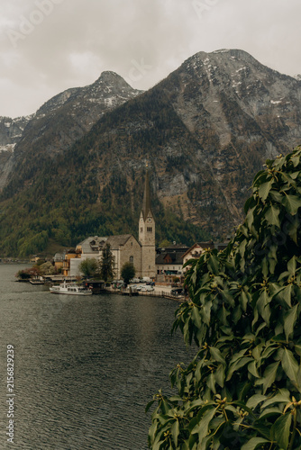 Konstfotografi Hallstatt village church and Austrian Alps framed by green foliage
