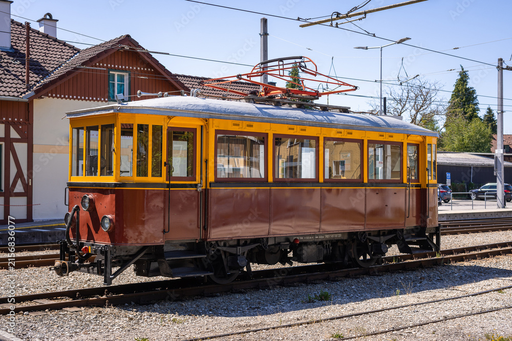 Fototapeta premium A classic vintage electric railcar with a yellow and brown wooden body parked outside the train depot at Attersee on a sunny day.
