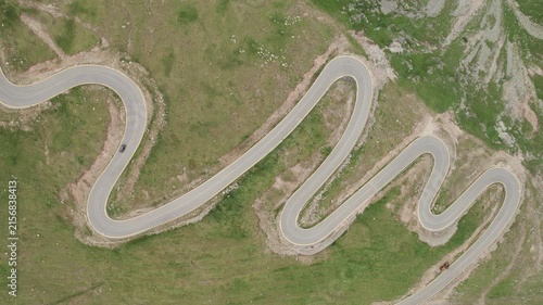 Aerial tracking shot of a car driving on the winding Transalpina mountain road in Romania