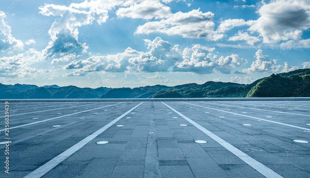 Fototapeta premium Empty paved plaza floor and green mountains under blue sky as background