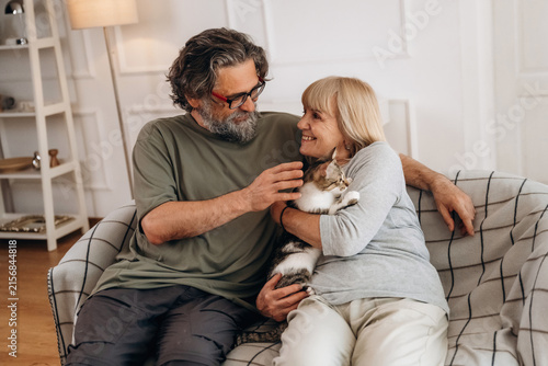 Cuadro en lienzo Middle-aged couple sitting on a couch in a cozy living room, smiling and interac