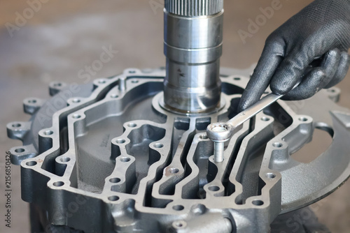 Fotografie Mechanic tightening a bolt on a transmission casing with a wrench