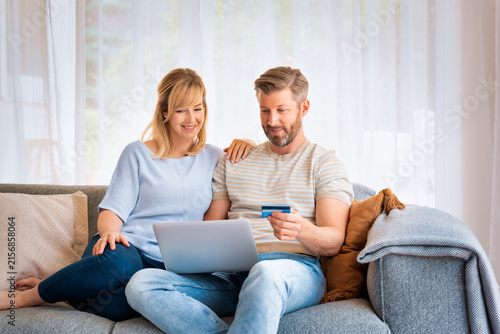 Rear view shot of a middle-aged couple using a credit card and laptop at home