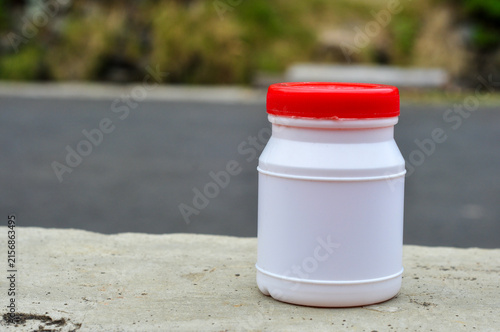 Blank White Plastic Bottle with Red Cap Outdoors