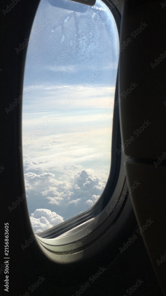 Fototapeta premium View of Clouds and Blue Sky Through an Airplane Window